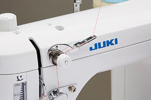 The sub-tension unit on the right of the JUKI Haruka TL-18QVP head, with thread running through it toward the needle.