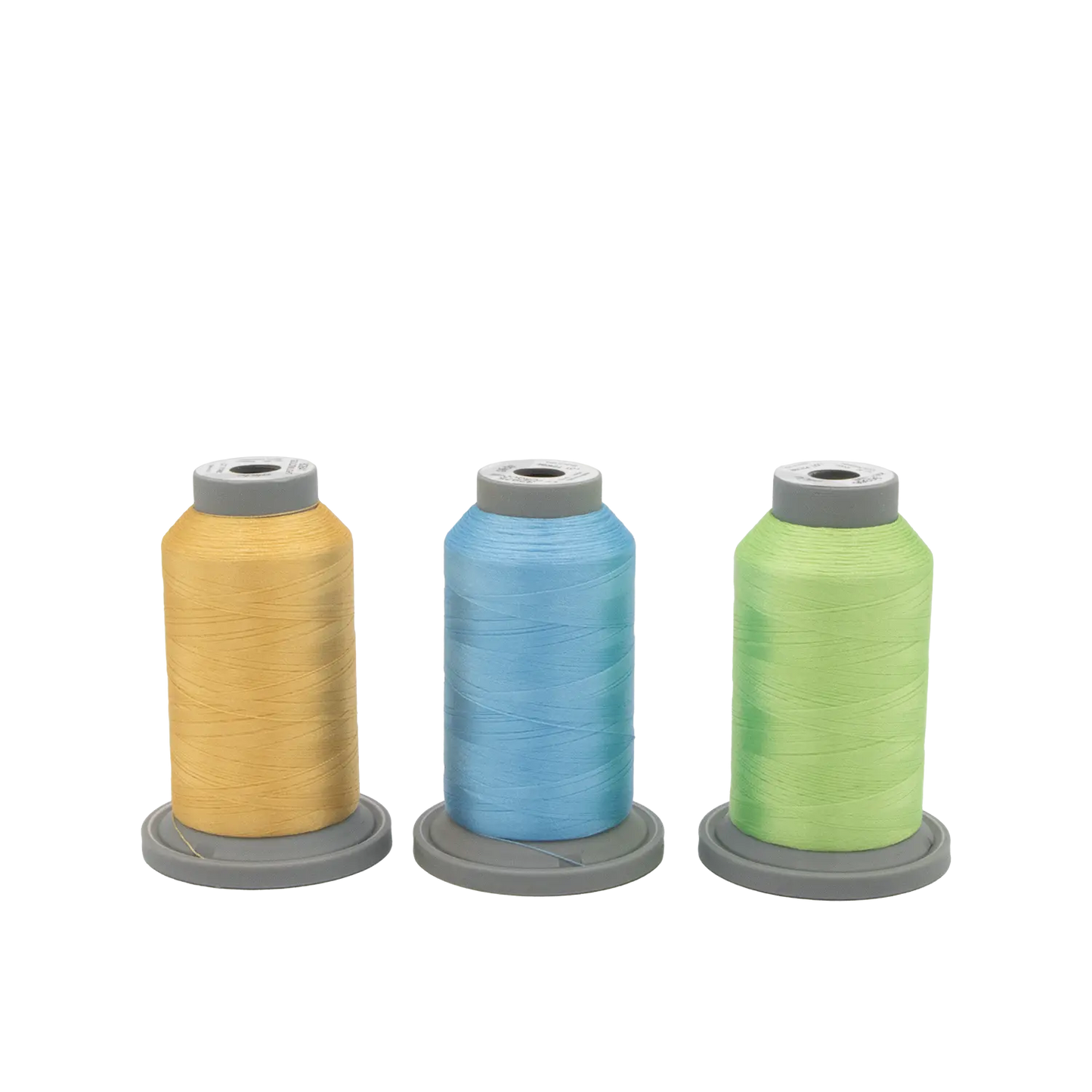 Three spools of Hab+Dash by Fil Tec's Sugar Stitches Glide Thread of the Month Bundle in yellow, blue, and green stand upright on gray bases against a plain white background—ideal for your stitching projects.