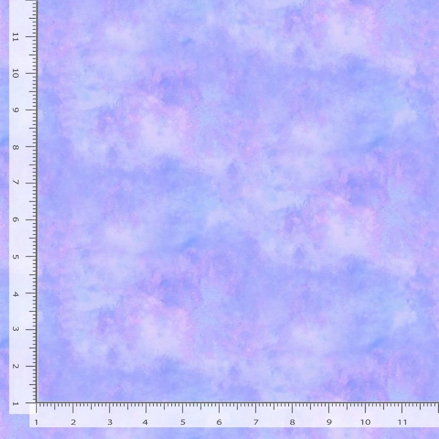 A square of Timeless Treasures Wild Beauty Lilac Water Color Texture fabric yardage, with a ruler on top and left edges (0–12 inches), displays a soft, cloudy quilt blender design in pastel purple and blue.