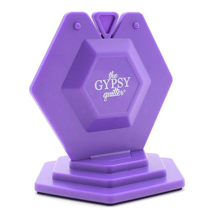 The Chain Piece Thread Cutting Gizmo by Tacony Corporation is a purple, hexagon-shaped thread cutter with top slots for easy thread insertion, resting on a matching base—perfect for cutting threads during your sewing projects.