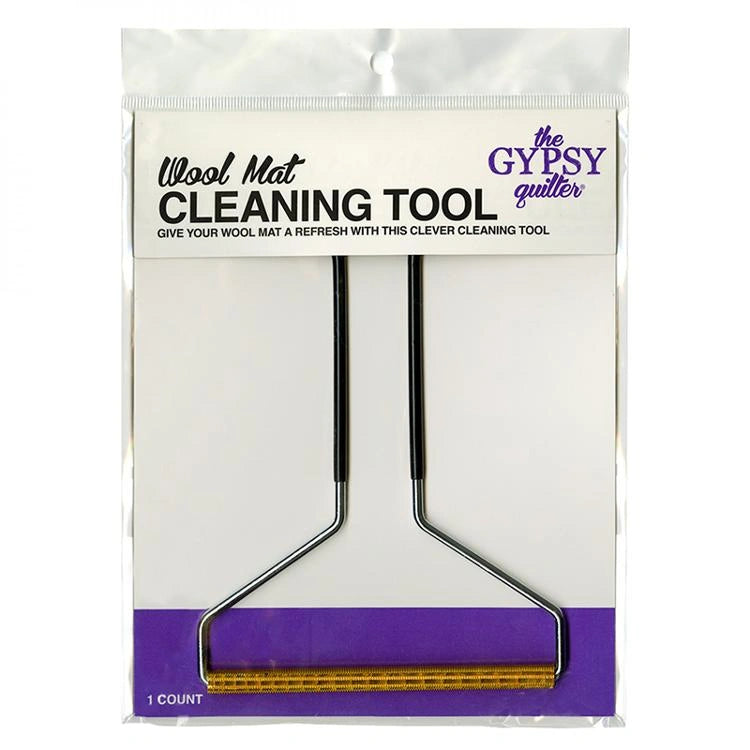 The Wool Mat Cleaning Tool by The Gypsy Quilter has a metal handle and wooden roller for cleaning pressing mats. It comes packaged in white and purple.