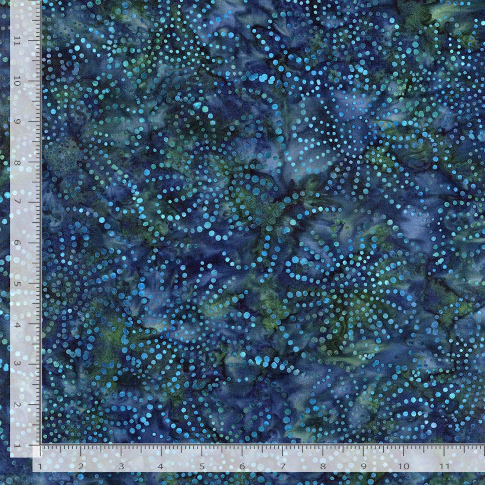 A fabric square of Tonga Midnight Raindrops Batik Fabric Yardage features blue and green dotted circular designs on a dark background, shown next to a 12-inch ruler. This Timeless Treasures Fabrics piece has lighter blue and green spots.