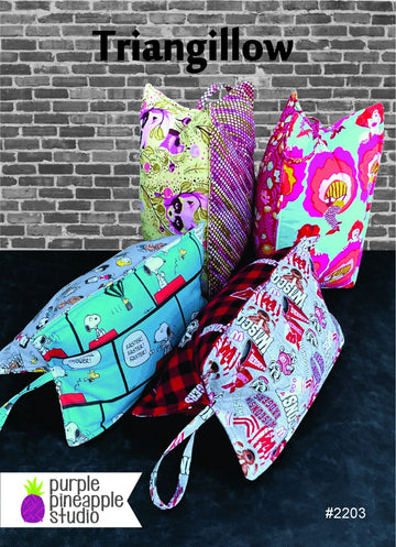 Five vibrant, triangular fabric bags with handles stand against a brick wall, each showcasing playful designs made with the Triangillow Quilt Pattern by Purple Pineapple Studio. The text reads Triangillow and #2203.