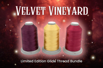 Three large spools of Hab+Dash by Fil Tec Glide thread in purple, yellow, and deep red are shown against a warm background. “Velvet Vineyard Glide Thread of the Month Bundle” is displayed at the top.