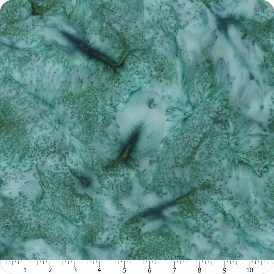 A close-up of Hoffman 1895 Watercolors Sea Mist Batik 108" wide quilt backing shows teal and green marbled fabric with organic, flowing shapes. A white ruler along the edge displays inches from 0 to 12.