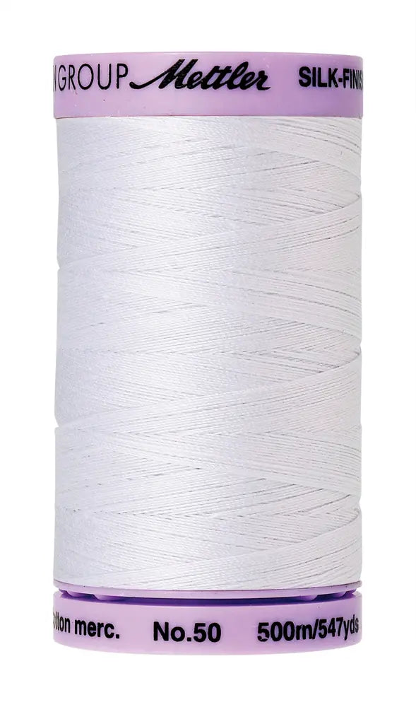 A 500m spool of Mettler Cotton Silk Finish 50wt sewing thread in white, ideal for quilting or all-purpose stitching, with a light purple cap and base showing brand info.