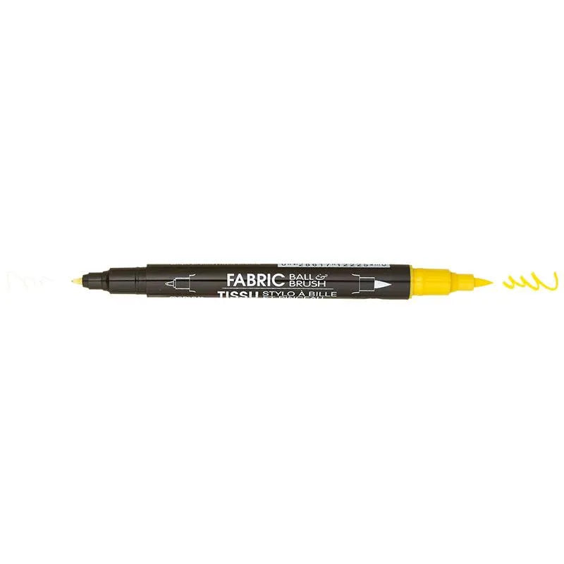 The United Notions Marvy Fabric Ball & Brush Marker in black, with a fine point and brush tip, is shown drawing a yellow squiggle from its brush end.
