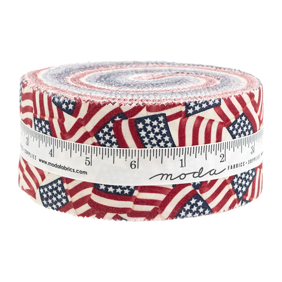 The America 250 Years Jelly Roll by United Notions features rolled fabric strips with overlapping American flags, wrapped in a white measuring tape-printed ribbon and branded with “moda.”.