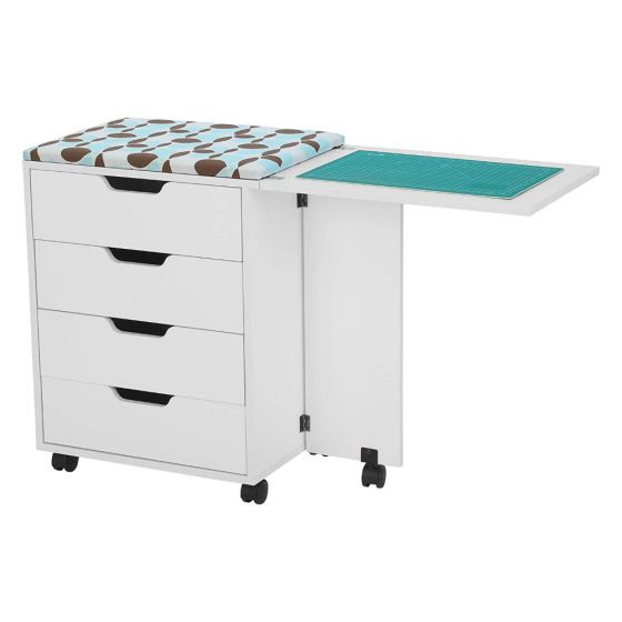 The Arrow Laverne and Shirley Sewing and Quilting Machine Cabinet by Arrow Companies, LLC features four drawers, a patterned cushioned top, and an extended side table with a green cutting mat for organized crafting storage and convenience.