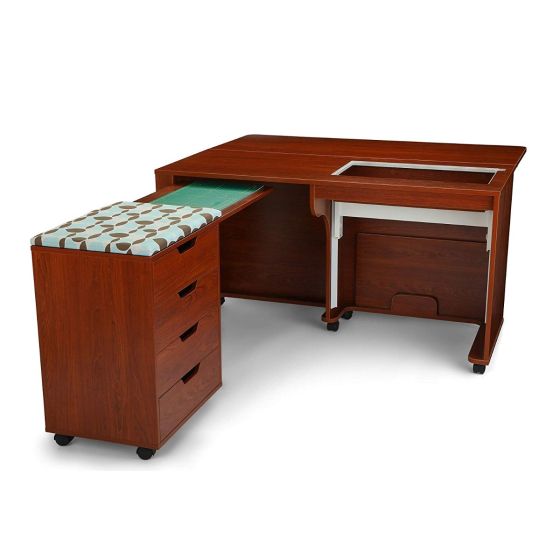 The Arrow Laverne and Shirley Sewing and Quilting Machine Cabinet by Arrow Companies, LLC is an L-shaped wood cabinet with an extendable section, three drawers, a cushioned seat in blue/brown leaf pattern, and an open compartment for your sewing or quilting machine.