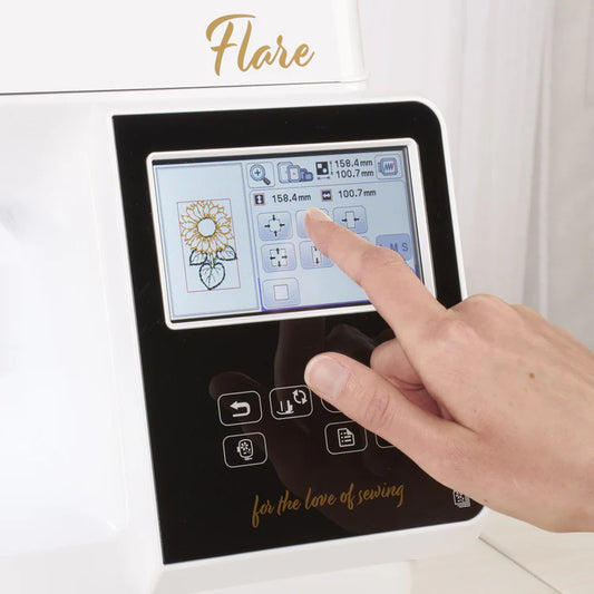 A hand touches the touchscreen of the Baby Lock Flare Dedicated Embroidery Machine with FREE Online Classes, showing an embroidery sunflower pattern, design settings, fonts, and the words "Flare" and "for the love of sewing" on the machine.