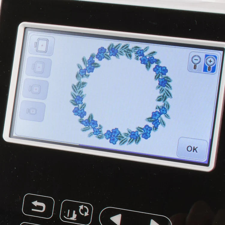 The Baby Lock Flare Dedicated Embroidery Machine with FREE Online Classes features a digital screen showing a circular wreath embroidery pattern of green leaves and blue flowers, plus icons and an OK button below the design.