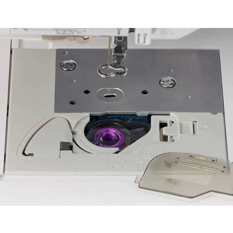 Close-up of the Baby Lock Flare Dedicated Embroidery Machine with FREE Online Classes, highlighting its bobbin case, metal needle plate, purple plastic bobbin, and a partially open transparent cover.