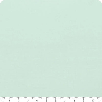 A 10" Bella Solids Home Town Sky Junior Layer Cake square by United Notions in light mint green with subtle texture, shown with a white inch ruler for scale. The fabric swatch has rounded corners.