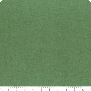 A square piece of Confetti Cotton™ Lodge Pole Solid Fabric by Riley Blake is shown against a white background with a ruler below (0–11 inches) for scale. The green fabric has a subtle texture and slightly rounded corners.