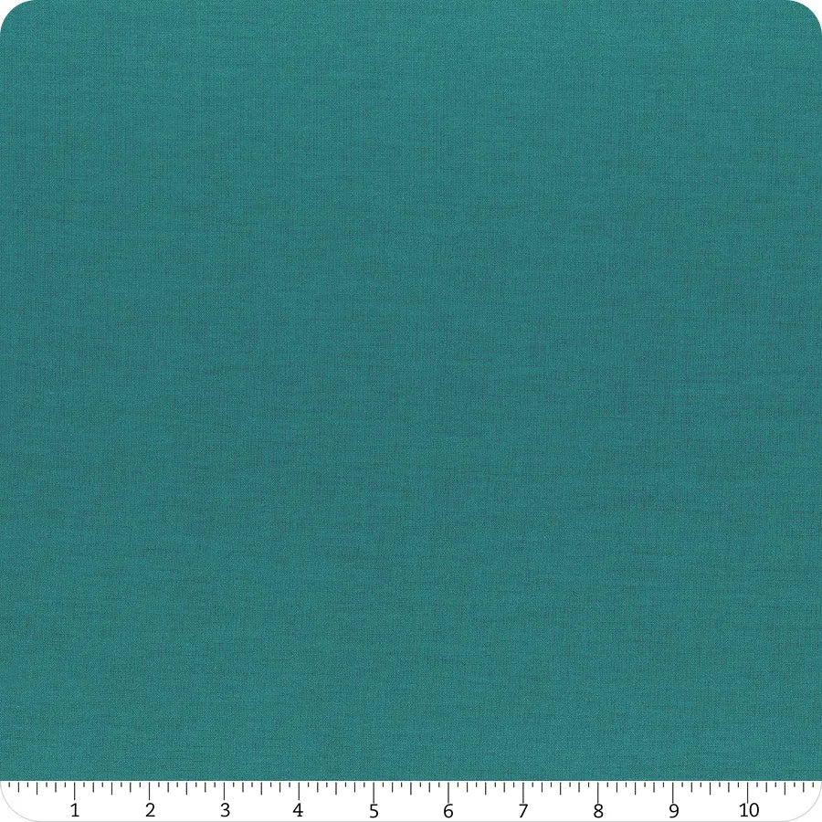 A swatch of Riley Blake Confetti Cotton™ Oceanside Solid fabric is shown with rounded corners and a woven texture. A ruler at the bottom measures the quilting cotton in inches from 0 to 12 for scale.