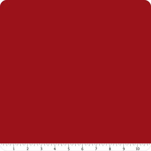 A square swatch of solid deep red Confetti Cotton™ Cherry Tart fabric by Riley Blake with rounded corners and a white ruler along the bottom showing inches 1 to 10—ideal for quilting cotton projects.