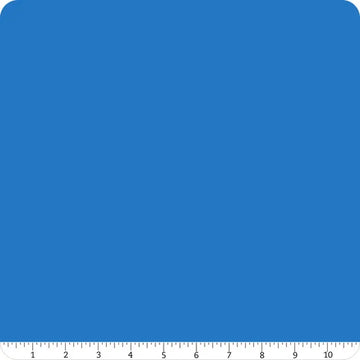 A square with rounded corners in solid blue, resembling Confetti Cotton™ Cobalt Solid Fabric Yardage by Riley Blake. A white ruler marked 1–10 inches lines the bottom, ideal for quilting cotton fabric projects.