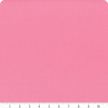 A square of Riley Blake's Confetti Cotton™ Piglet Pink Solid Fabric is shown on a white background, featuring subtle texture. A ruler at the bottom edge marks measurements from 0 to 10 inches.