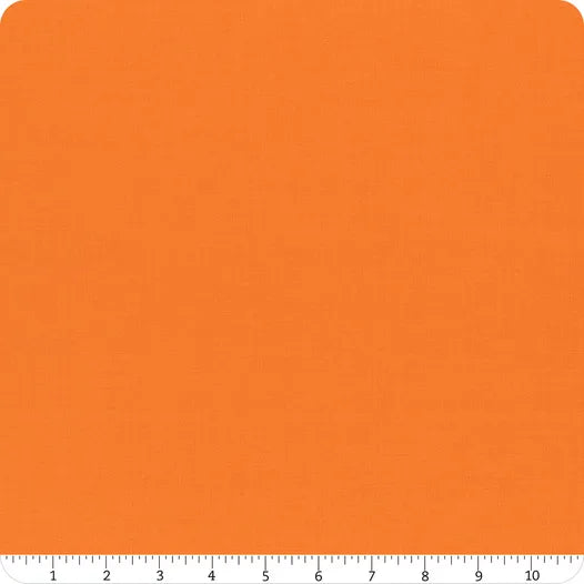 A square sample of Riley Blake's Confetti Cotton™ Tangerine Fabric Yardage is pictured with a white ruler marked 1 to 10 inches along the bottom edge. The quilting cotton has rounded corners.