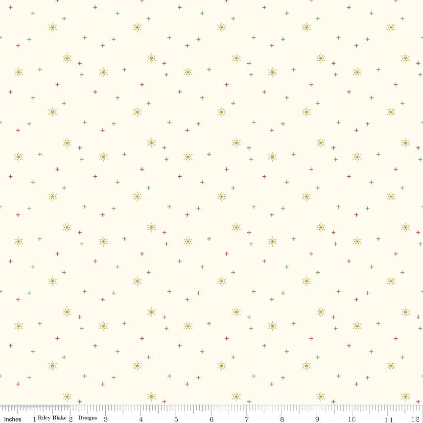 Sparkler Cotton Snowflake Fabric Yardage by Riley Blake features cream fabric with scattered red and green plus signs and yellow starburst shapes. A ruler along the bottom edge marks inches from 1 to 12.