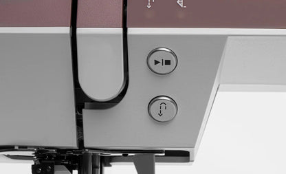 Close-up of two metallic buttons on the Pfaff Quilt Ambition 635 Sewing and Quilting Machine by Quilted Joy, featuring a triangle and a curved arrow symbol, both near the stitching area with Integrated Dual Feed Technology.