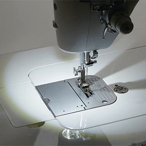 The lit needle area of the JUKI Haruka TL-18QVP, showing the throat plate and presser foot under the LED.