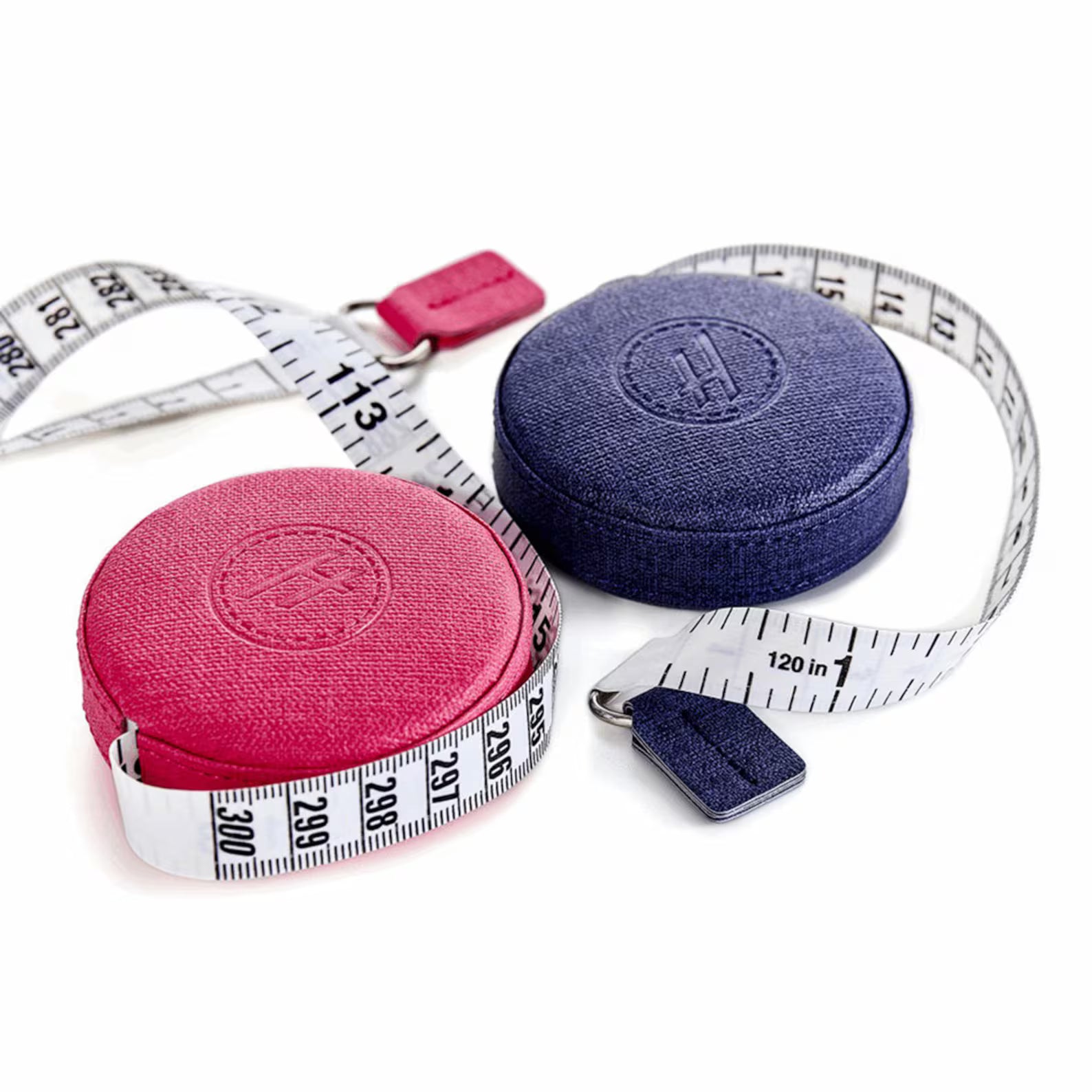 The Baby Lock Hemline 120in Retractable Tape Measures feature pink and navy faux leather cases with matching pull tabs. White fiberglass tape with black markings extends partly between the two stylish, round cases.