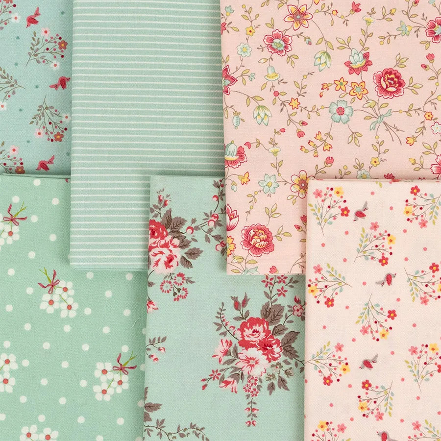 Lyda Rose Mini Charms by United Notions includes five pastel fabric pieces with stripes, polka dots, and Bunny Hill Designs’ floral prints in pink, red, and yellow—arranged in a neat, overlapping layout.