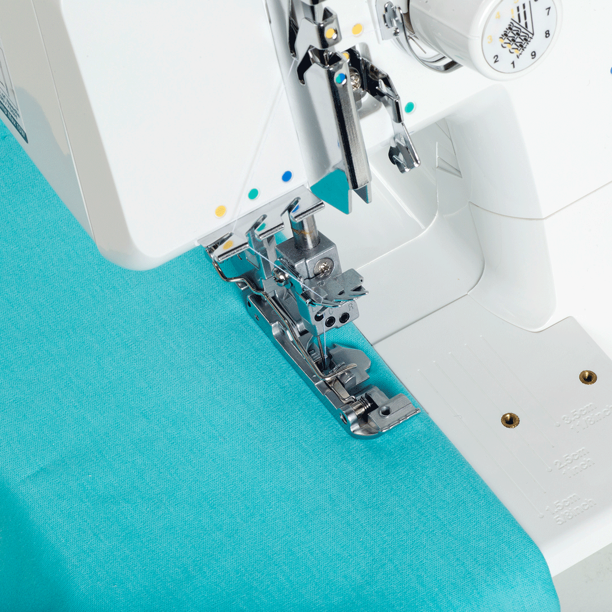 A coverstitch being sewn on teal knit fabric by the JUKI MCS-1700QVP, with the presser foot and needles at work.