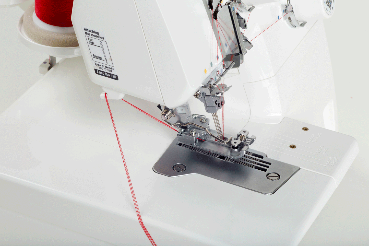 The JUKI MCS-1700QVP threaded with red thread from a cone, showing the three needles, the presser foot and the throat plate.