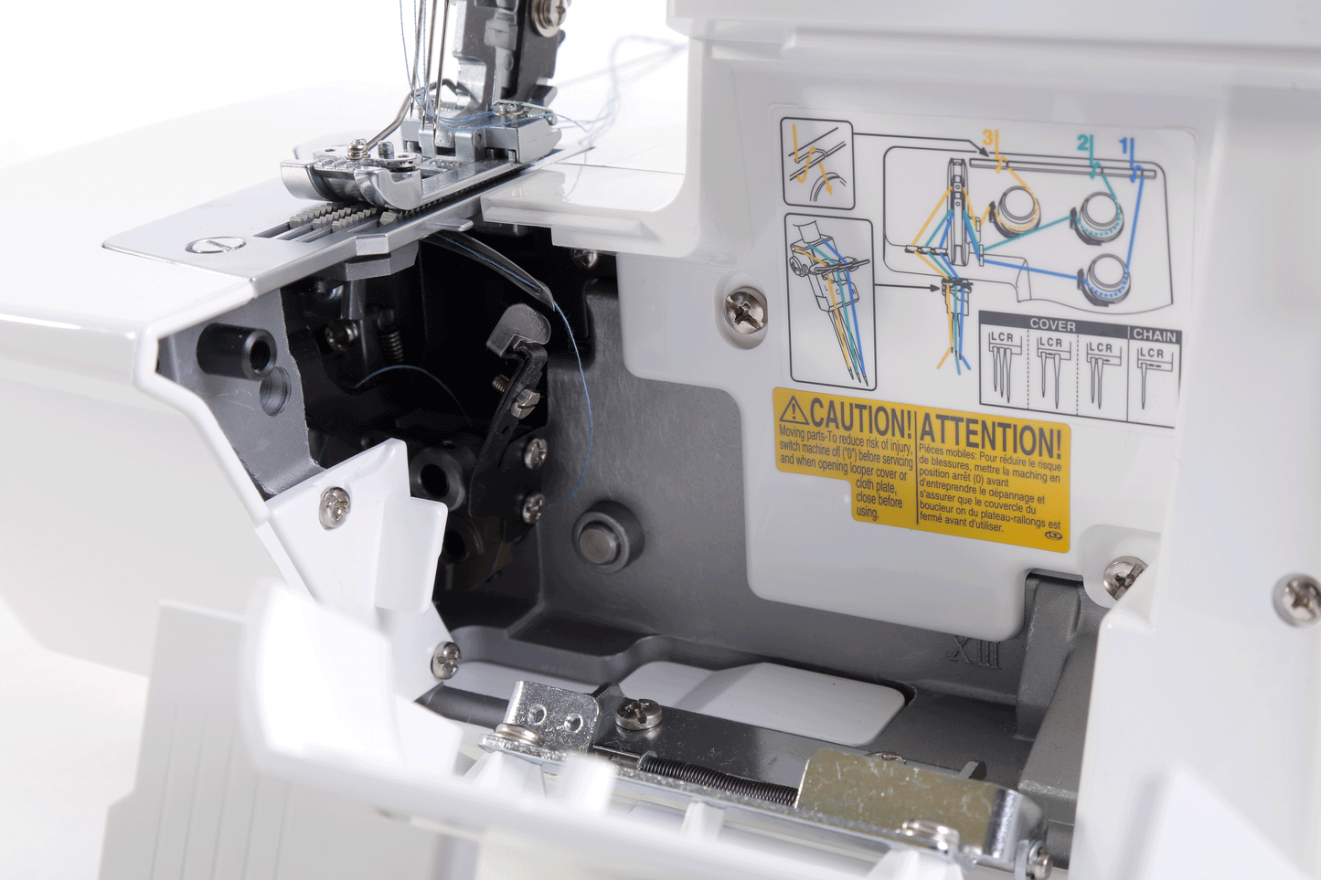 The looper cover of the JUKI MCS-1700QVP swung open, showing the lower looper mechanism and the color threading diagram printed inside the cover.