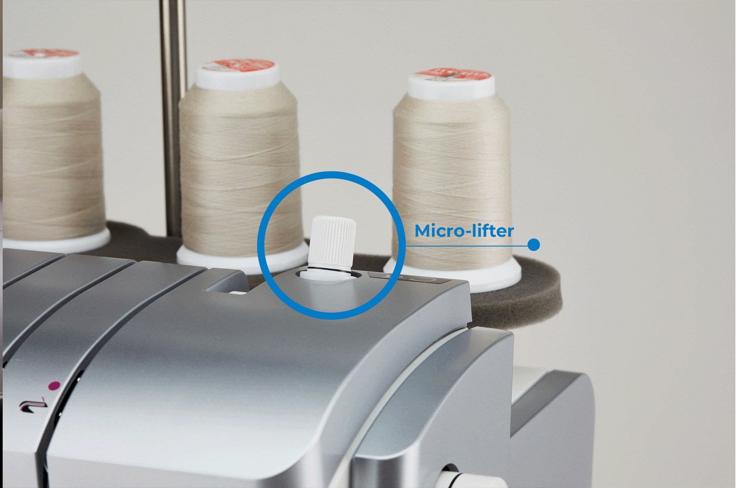 The micro-lifter lever on top of the JUKI Akane MO-3000QVP, circled and labeled, with thread cones standing behind it.