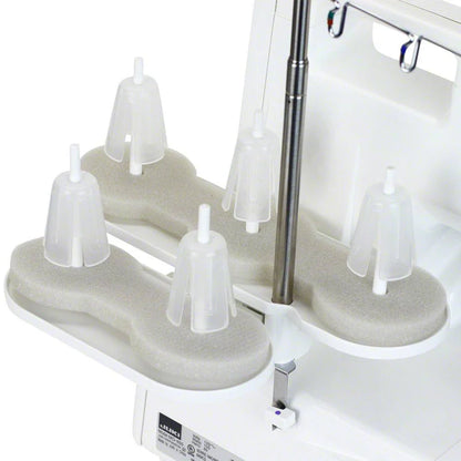 Close-up of a dental instrument holder with four plastic covers on foam, attached to a white dental unit—crafted with precision akin to the Juki America Pearl Line MO-655 2/3/4/5 Thread Serger.