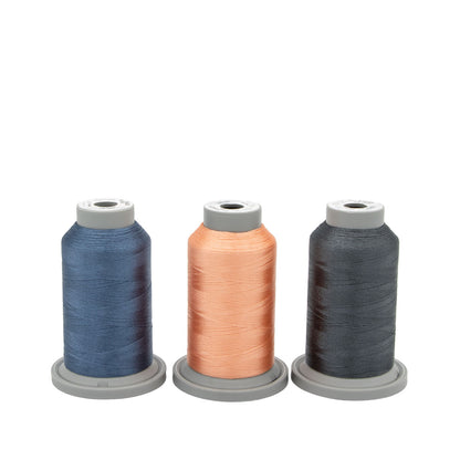 The Moonlight Tides Glide Thread of the Month Bundle by Hab+Dash by Fil Tec features three large spools in blue, peach, and dark gray—ideal for embroidery or quilting—each upright on a gray base against a white background.
