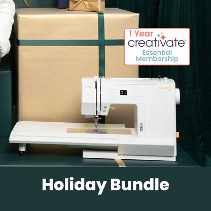 A white SVP Pfaff Passport 3.0 sewing machine with IDT System is on a table before a large green gift box with gold ribbon and a "1 Year Creativate Essential Membership" sign. Below, text reads "Holiday Bundle.