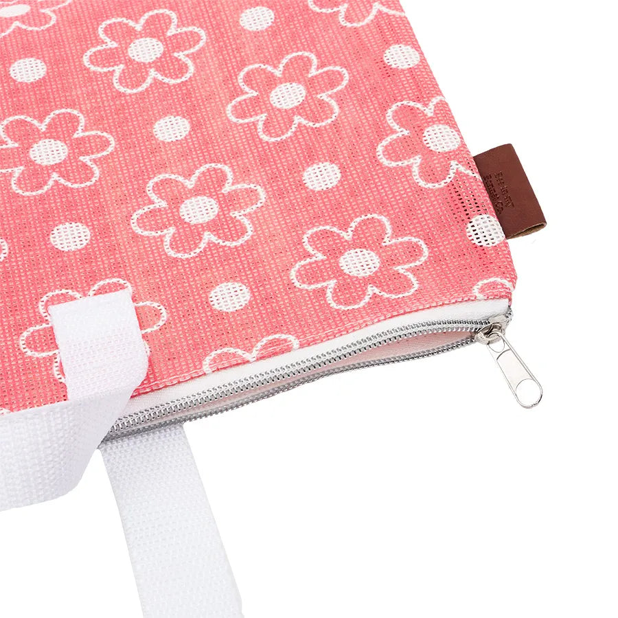 A close-up of the Big Daisy Project Bag by Lori Holt, featuring pink fabric with white flowers and polka dots, a white zipper and strap, plus a brown side tag—ideal for storing your quilting accessories.