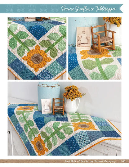 A table topper made with Lori Holt patterns from the Checker Distributor Prairie Home Quilt Book, featuring sunflower and leaf designs in blue, green, yellow, and white—shown on a table with blue canister and yellow flowers.