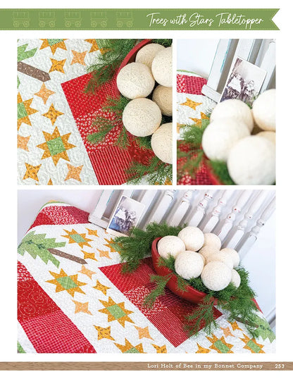 A festive tabletop display showcases a quilt inspired by the Checker Distributor Prairie Home Quilt Book, paired with a red textured bowl of cream decorative balls, faux greenery, and framed vintage-style photos.