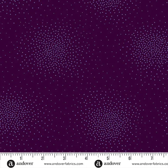Spritz Plum Fabric Yardage by Andover features dark purple fabric with clusters of light purple dots in a starburst pattern. A white ruler labeled “andover” and “www.andoverfabrics.com” marks inches at the bottom.