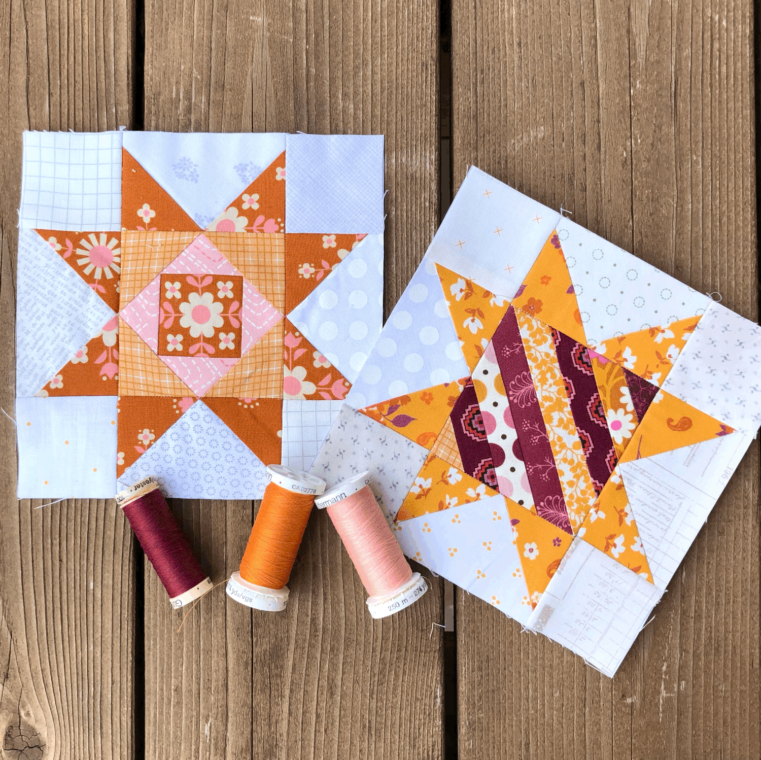 Quilted Joy's Scrappy Stars quilt blocks showcase vibrant orange, yellow, and purple fabrics on a wooden surface, with four matching thread spools in front. Made using paper piecing for precise star patterns.