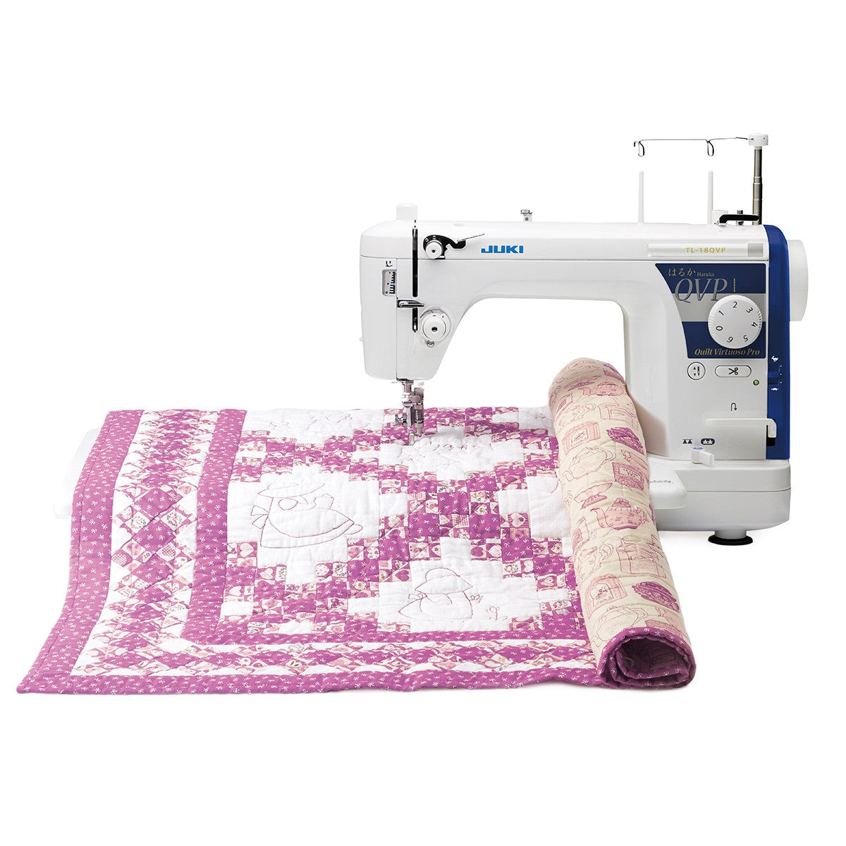 The JUKI Haruka TL-18QVP with a pink and white quilt rolled and draped in front of the extension table.