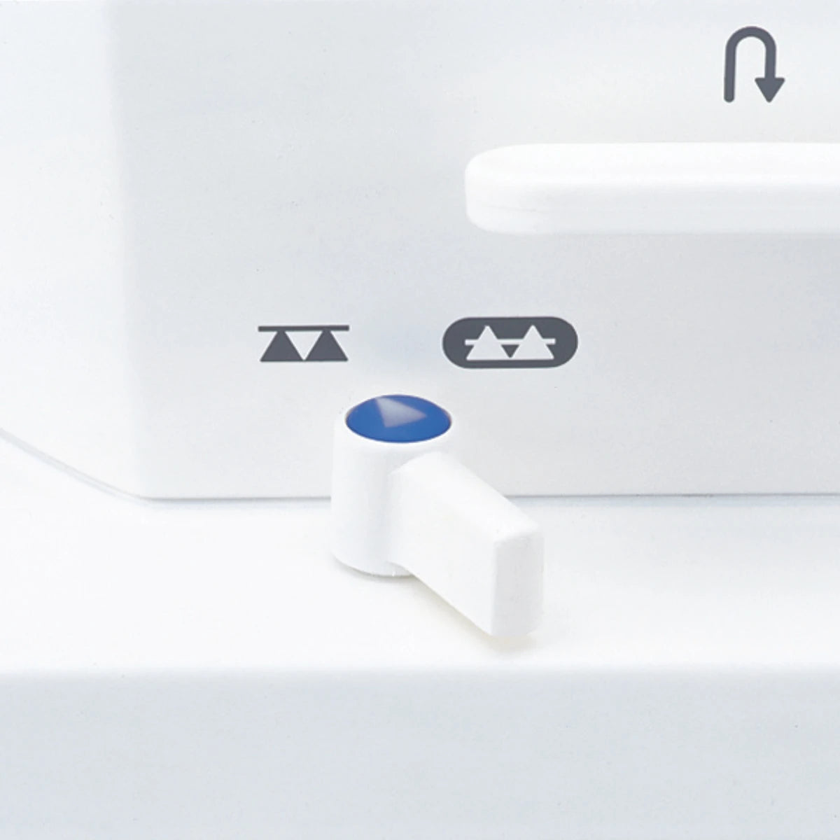 The drop feed lever on the JUKI TL-15 with the raised and lowered feed dog icons printed beside it and the reverse arrow above.