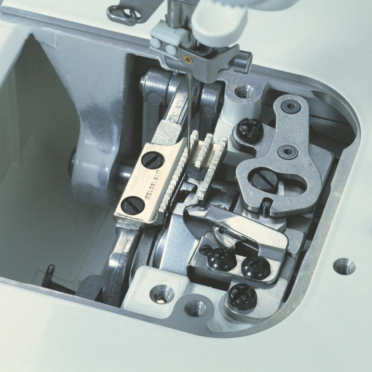 The face plate of the JUKI TL-15 removed to show the internal take-up and presser bar mechanism in cast metal.