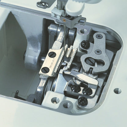The face plate of the JUKI TL-15 removed to show the internal take-up and presser bar mechanism in cast metal.