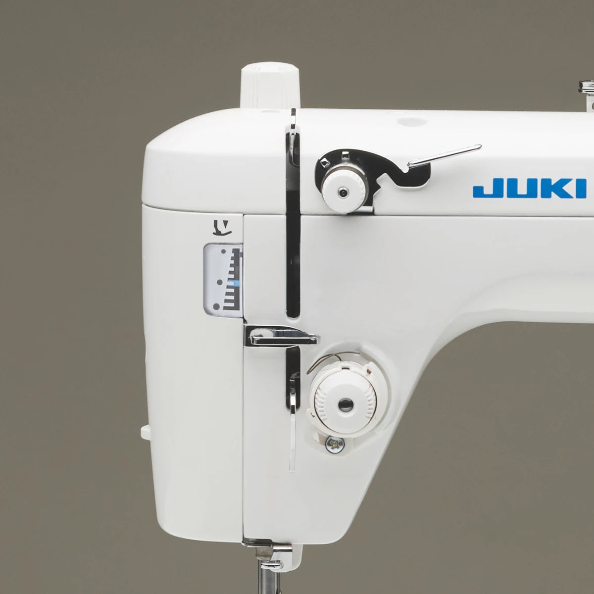 The right side of the JUKI TL-15 head against an olive backdrop, showing the sub-tension unit and the thread guide running down to the needle.