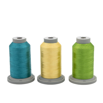 Three spools of Hab+Dash by Fil Tec Glide thread—teal, yellow, and green—stand side by side on gray bases, forming the Topaz Tropics Glide Thread of the Month Bundle, ideal for quilting or embroidery, set against a white background.