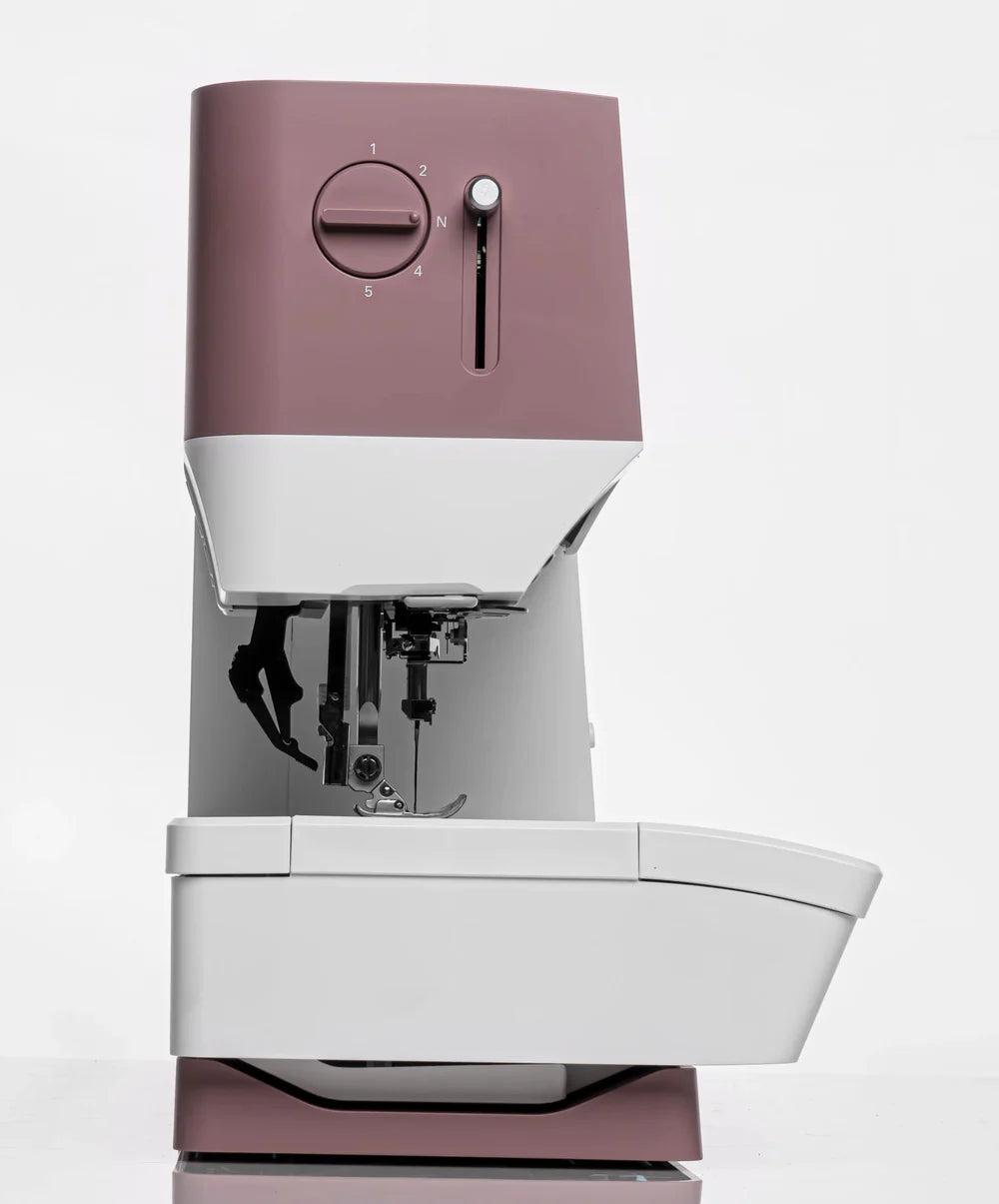 The Quilted Joy Pfaff Quilt Ambition 635 Sewing and Quilting Machine features a sleek white and mauve design with simple dials and Integrated Dual Feed Technology, shown against a plain white background.