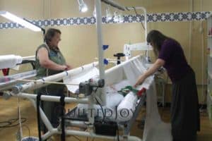 Volunteers load the APQS machines with LOTS of backing and batting to quilt more than 50 charity quilts in a day!