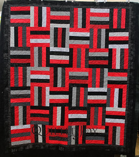 Karen made this Rail Fence quilt for her son and she has lots of hidden meanings in it's design. It's red, black, and grey, because he's an avid UofL supporter and it's quilted with footballs because he played while growing up.
